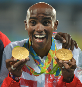 Mo Farah shows off his medals at the podium during the Rio 2016 Olympic Games. Photo By Tim Hipps, U.S. Army IMCOM Public Affairs . U.S. Army - via Wikimedia Commons. 