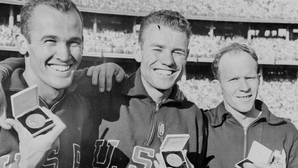 Hec Hogan, right, with his 100m bronze medal and first and second placegetters Bob Morrow and Thane Baker both from the US, at the 1956 Olympic Games in Melbourne. Photo: couriermail.com.au